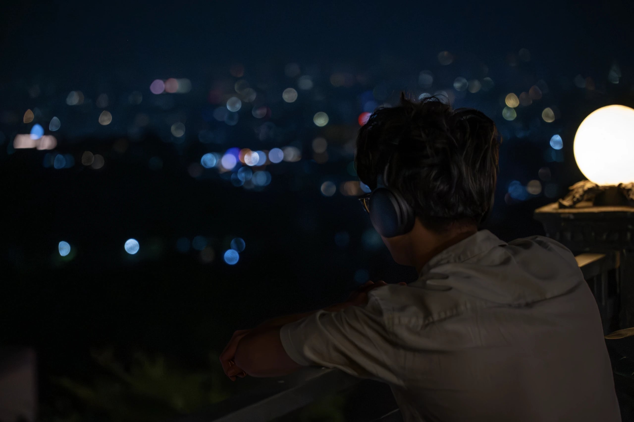 Artist wearing headphones looking out over a city skyline at night